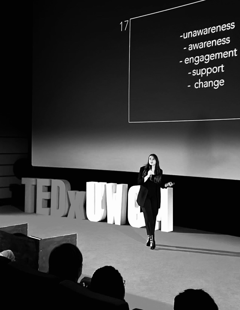 Sabine M. Probst Saavedra on stage holding a TEDx talk