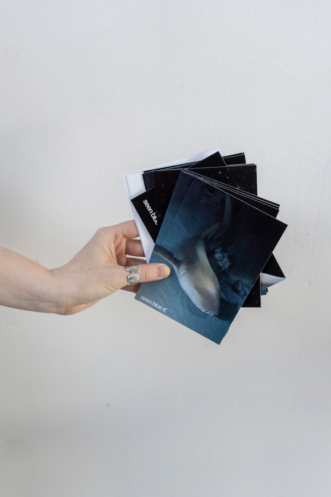 hand holding seen blue conservation postcards